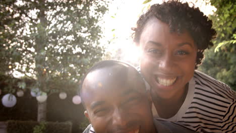 happy mixed race couple piggybacking in garden, close up