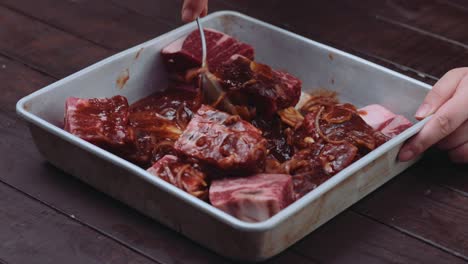 marinating raw meat ribs with sauce in a baking pan