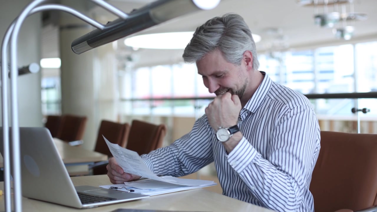 Professionista che revisiona documenti e celebra il successo in ufficio