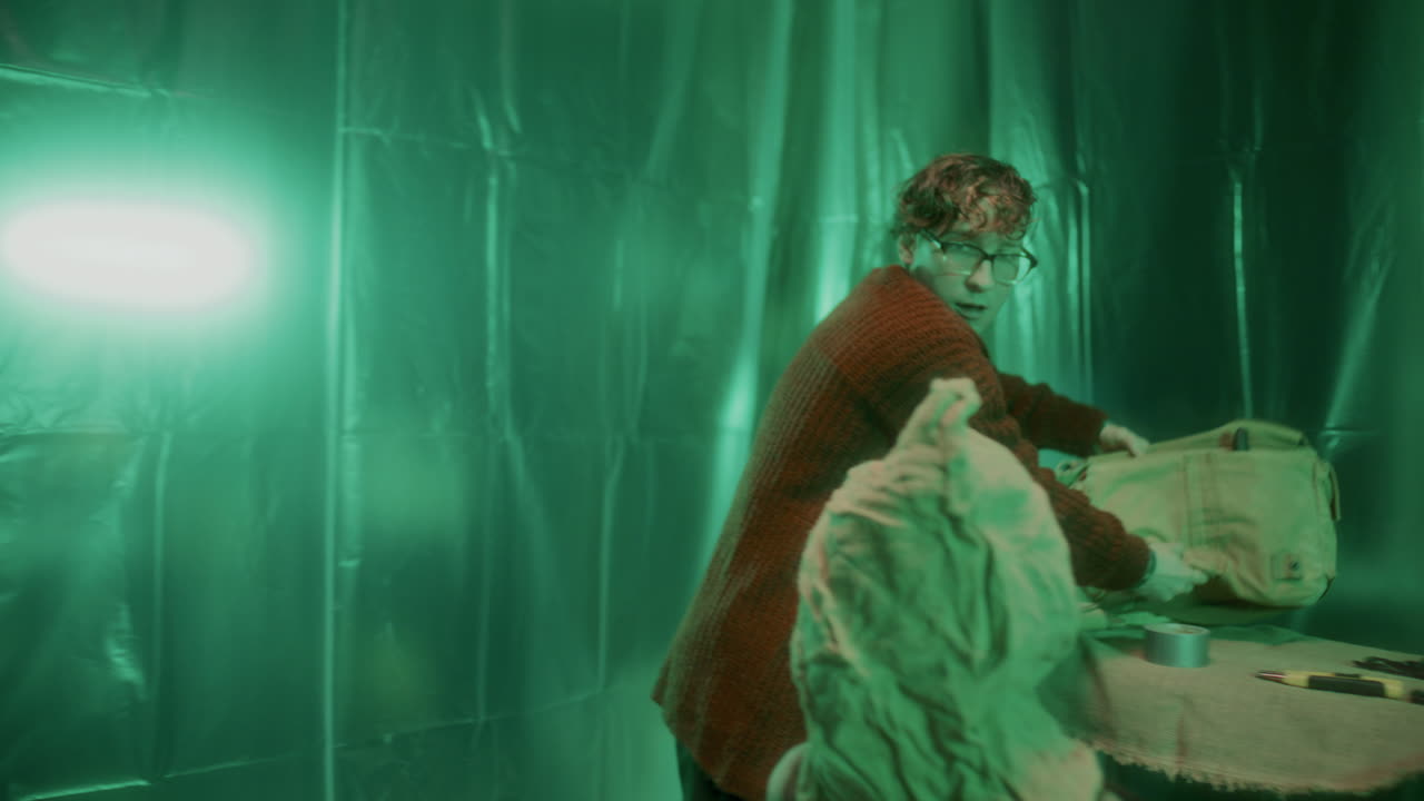 un asesino loco entra en la sala de tortura con una bolsa, intimidando a un rehén atado.