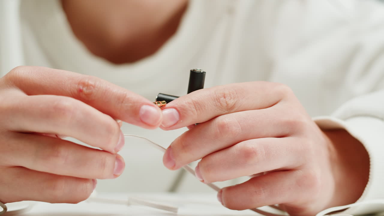 Young woman trying to untangle the headphones close-up. Special adapter for headphone. Tangled wires on table. Trying to untangle many messy cables