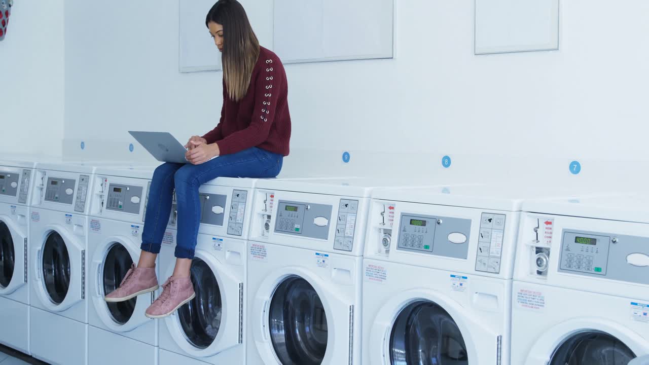 mujer sentada en la lavadora y usando portátil 4k