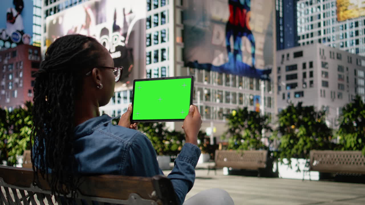 Schermo verde su tablet mostrato da una ragazza afroamericana che si rilassa in un parco in centro.