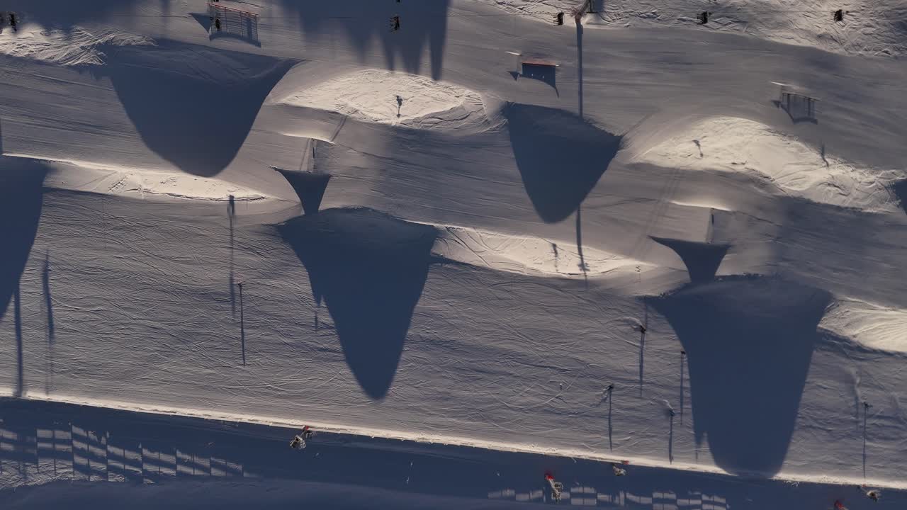 Aerial top down view of skiers, enjoying skiing and winter sports at Cardrona Ski Resort in New Zealand surrounded by stunning snow-covered mountains
