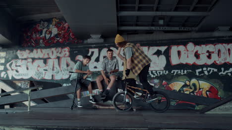 casual teenagers supporting man during preparing competition on bmx bike.