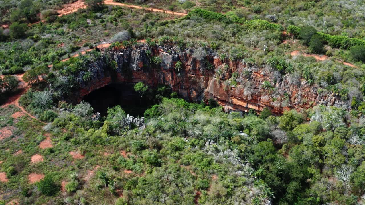 drone aéreo inclinándose hacia abajo y dolly en plano medio de la entrada de la cueva lapa doce con una selva tropical autónoma debajo en el parque nacional chapada diamantina en bahia, noreste de brasil