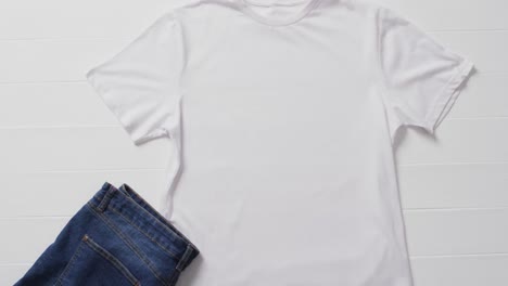 Video-of-white-t-shirt,-denim-trousers-and-copy-space-on-white-background