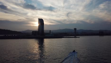 a fast small boat enters barcelona at sunset with beautiful silhouetted skyline in the background