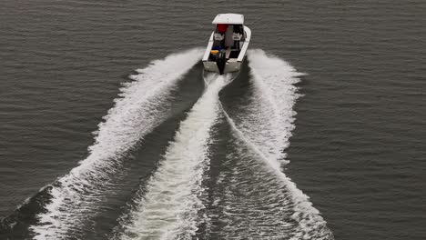 an aerial view, following a small white boat in a salt marsh off the south shores of long island, ny on a cloudy day