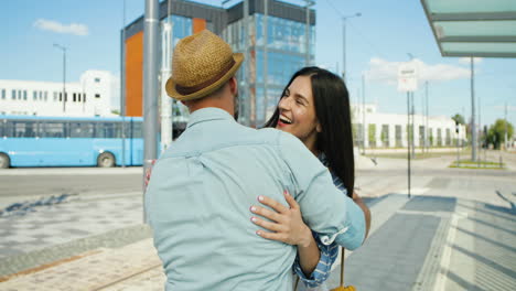 feliz pareja joven caucásica reunida en la estación de tren y abrazándose en un agradable día de verano