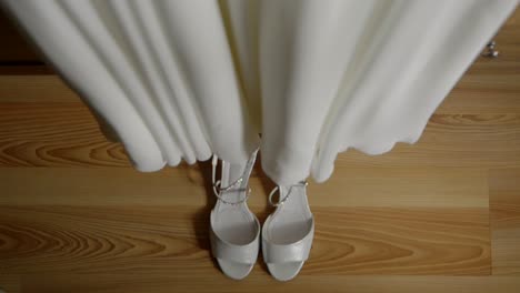 a flowing white wedding dress made of delicate fabric with white shoes placed underneath. bridal preparations for the wedding