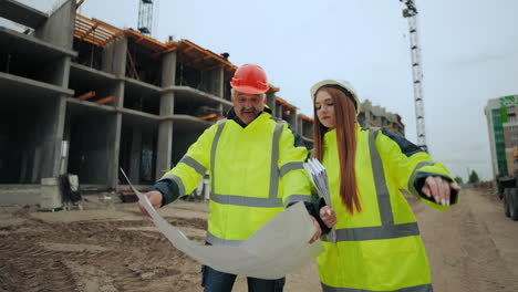una ingeniera de construcción y un capataz profesional de edad están discutiendo el plan de construcción en el sitio de construcción