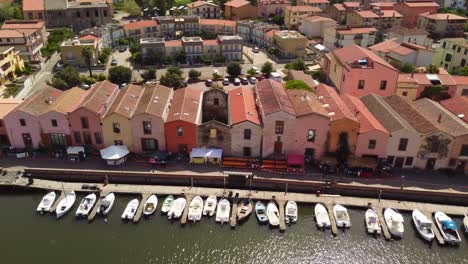 bosa colorful houses facing the river temo with boats docked, sideways, aerial