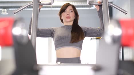 beautiful brunette girl doing pull-ups in the gym. a professional athlete performs strength exercises. 4k video