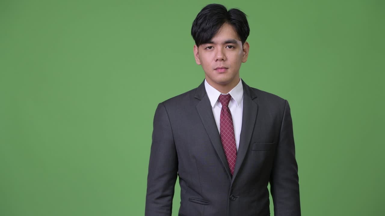 젊은 잘생긴 아시아 사업가가가 엄지손가락을 올리고 있습니다.