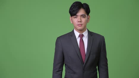 joven y guapo hombre de negocios asiático dando pulgares hacia arriba