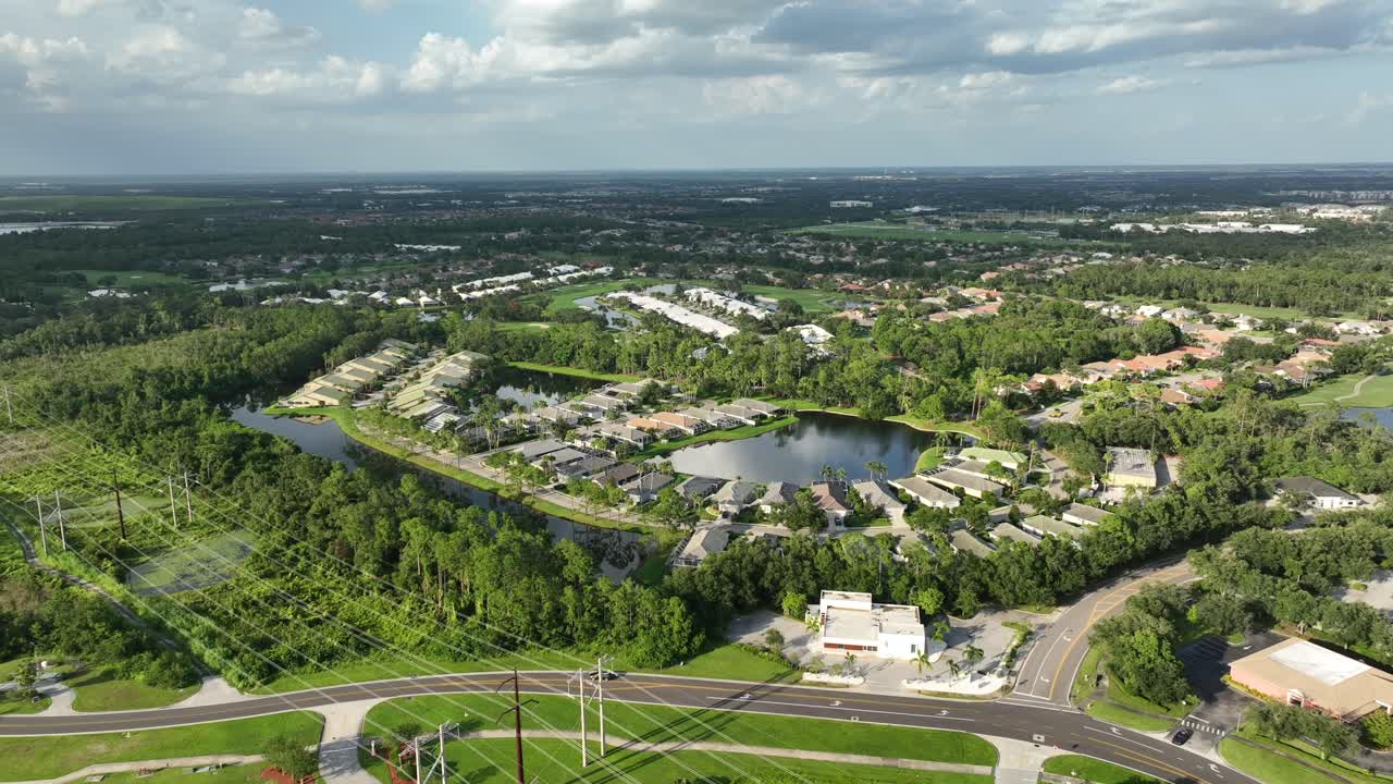 Rural street in luxury suburb district during golden sunset in Bradenton, Florida. Descend drone wide shot. Premium villas with natural lake in center of housing area. Peaceful landscape