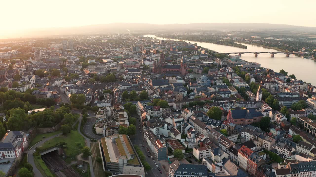 Sommersolnedgang. Drone over Mainz, Tyskland, cirkler rundt om den gamle bydel med Rhinen og en bro i baggrunden