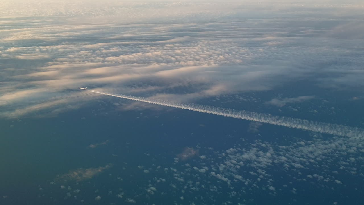vista increíble desde la cabina de un avión que vuela alto por encima de las nubes dejando un largo rastro de aire de vapor de condensación blanco en el cielo azul