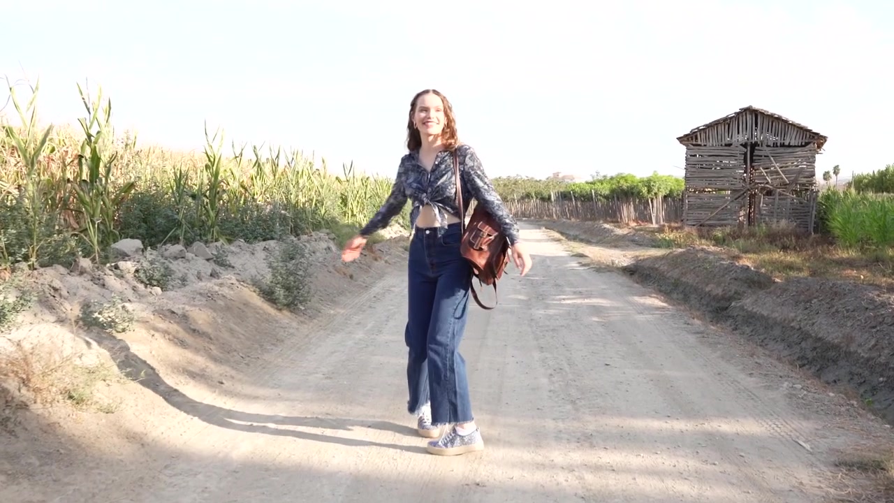Una donna si gode una passeggiata tranquilla attraverso il sereno paesaggio rurale lungo un sentiero polveroso