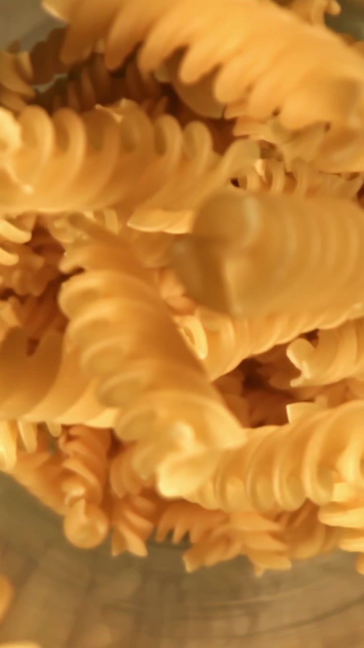 Close-up of Uncooked Fusilli Pasta Falling into a Container