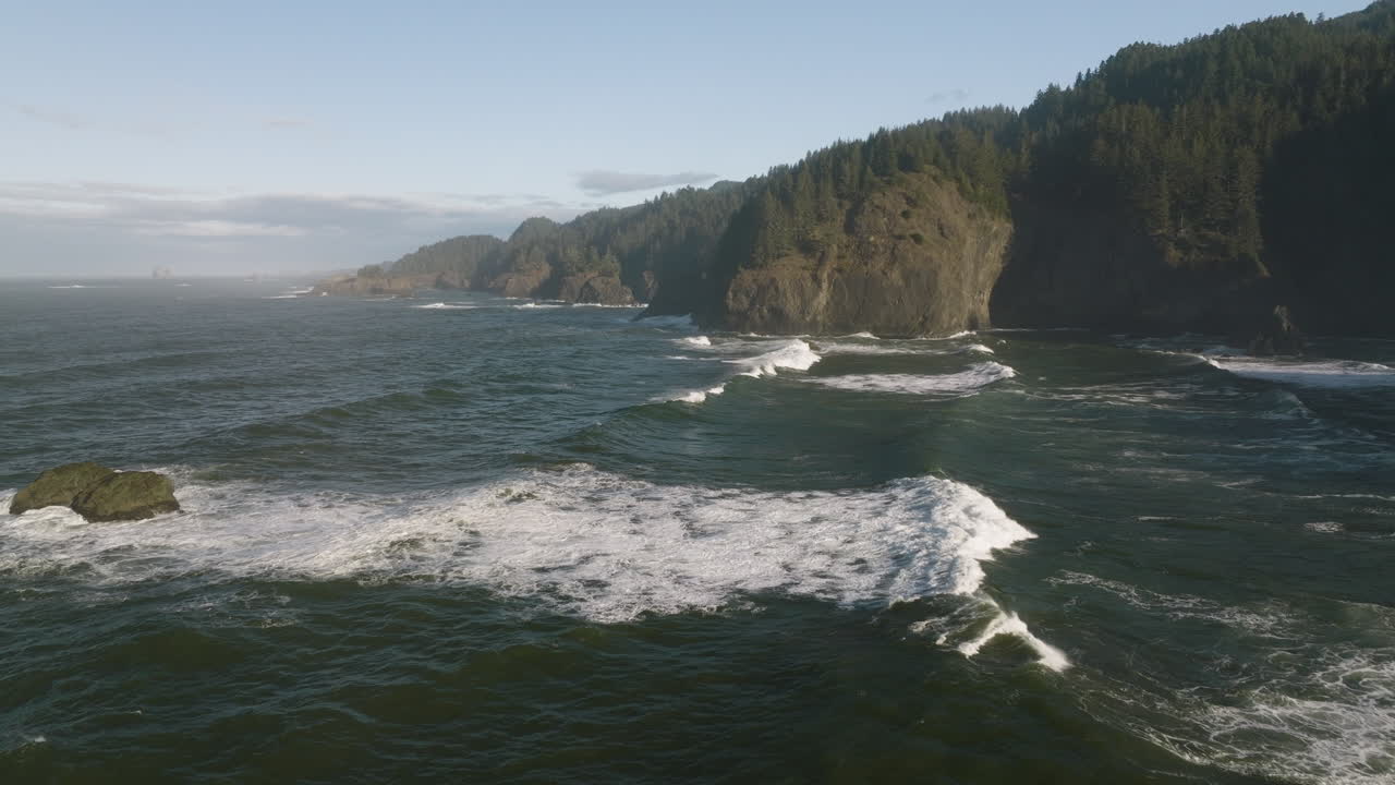 Aerial dolly of Cape Perpetua's rocky coastline on the Oregon Coast, with waves breaking against the cliffs