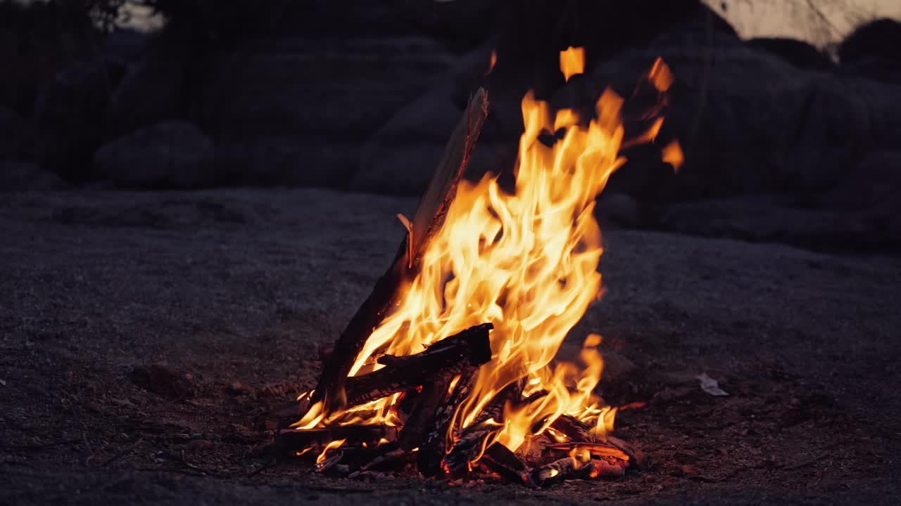 A closeup of a campfire. Beautiful fire burns brightly. Embers of the fire climb up. Slow motion