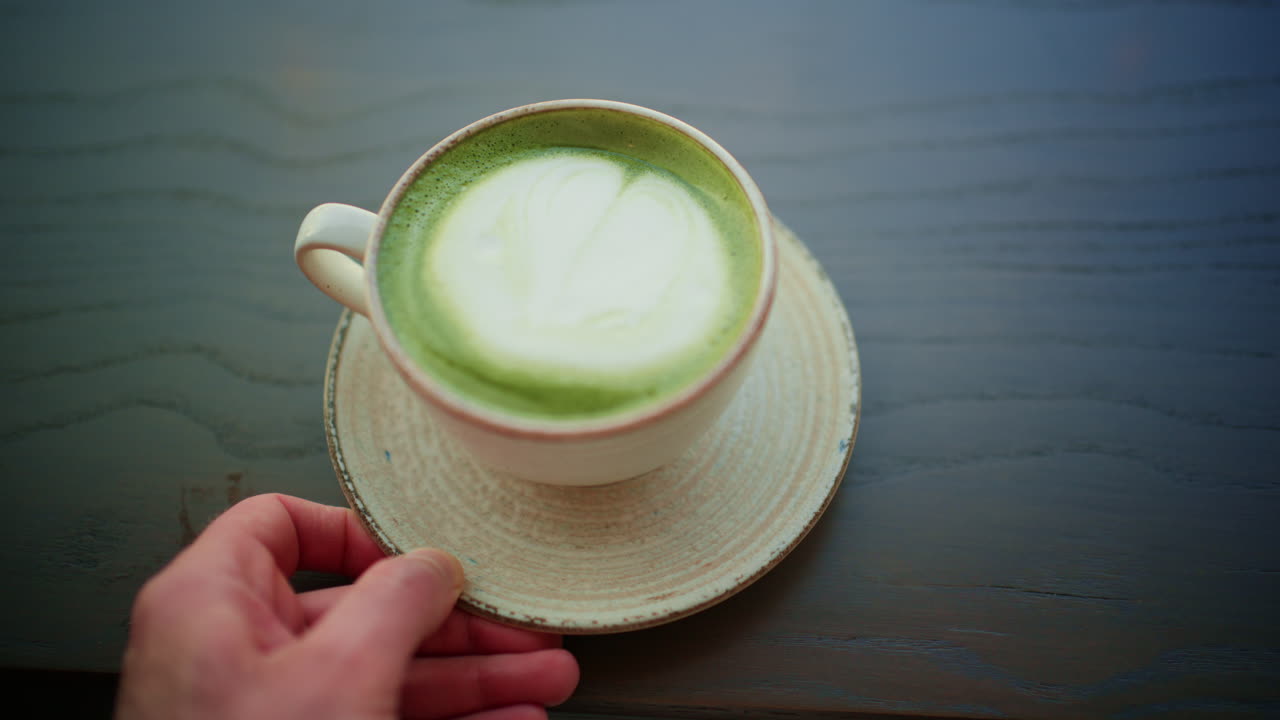 Vista superior de un latte de matcha con arte de espuma en una taza de cerámica