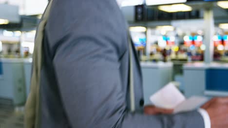 businessman using mobile phone while checking his boarding pass