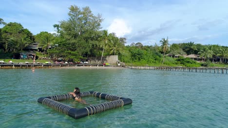 Girl-relaxing-in-a-floating-device-in-the-ocean,-Koh-Kood,-Thailand