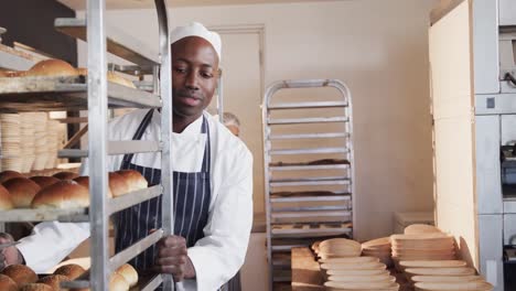 Happy-diverse-bakers-working-in-bakery-kitchen,-holding-baking-sheets-with-rolls-in-slow-motion