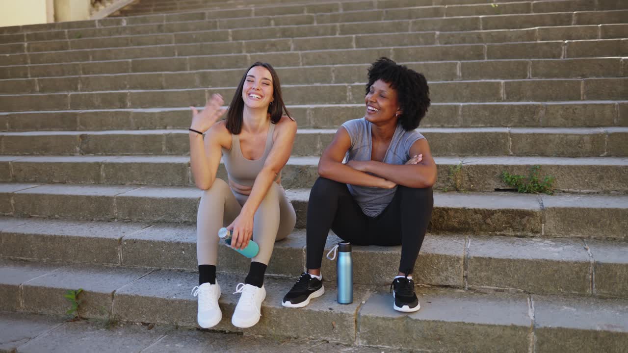 Amigos Multiétnicos Felizes Descansando e Rindo em Escadas da Cidade