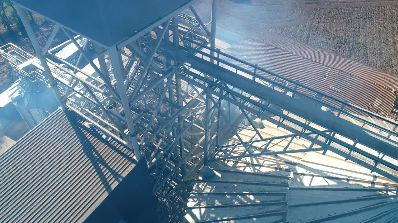 Modern factory in smoke. Exterior of grain elevators. Harmful vapor filling the air from industrial plant. Aerial view. Camera moving in around.