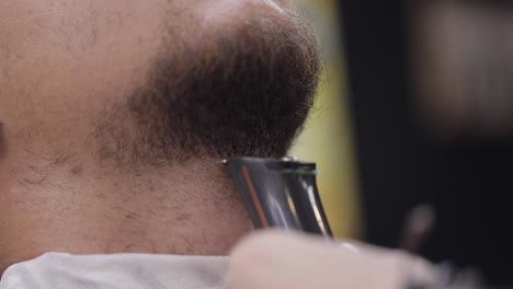 Barber-cutting-beard-using-electric-trimmer,-makes-haircut-for-groom-man-customer-at-barber-shop