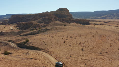 aerial passing over 4x4 car driving through scenic desert landscape