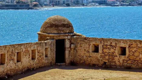 stone wall of venetian fortezza castle with sea and city at background in rethymno, crete, greece. panning shot