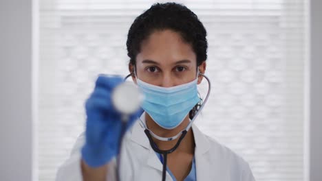 Portrait-of-mixed-race-female-doctor-putting-a-face-mask-on