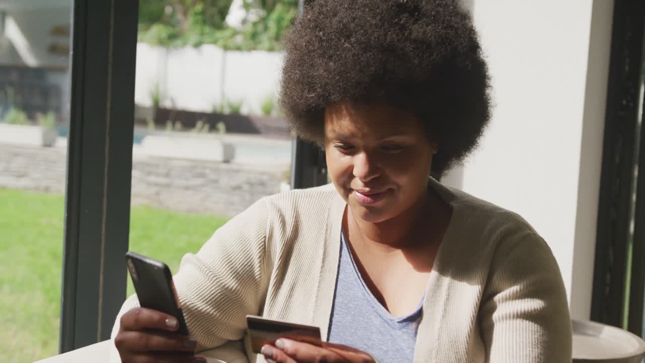 Video of happy plus size african american woman using two smartphones