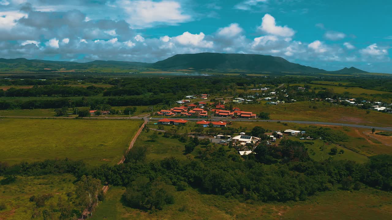 fry в сторону небольшого жилого района с оранжевой крышей в тропическом климате в пасмурный день с горой вдали.