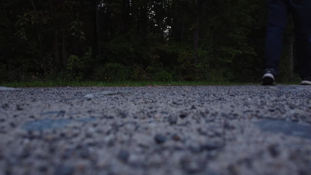 비포장 도로를 걷고 있는 청바지와 테니스 신발을 신은 사람의 사진