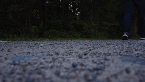 A-shot-of-a-person-in-jeans-and-tennis-shoes-walking-by-on-a-dirt-road