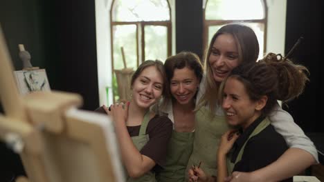 retrato de mujeres alegres en un taller mirando juntas obras de arte