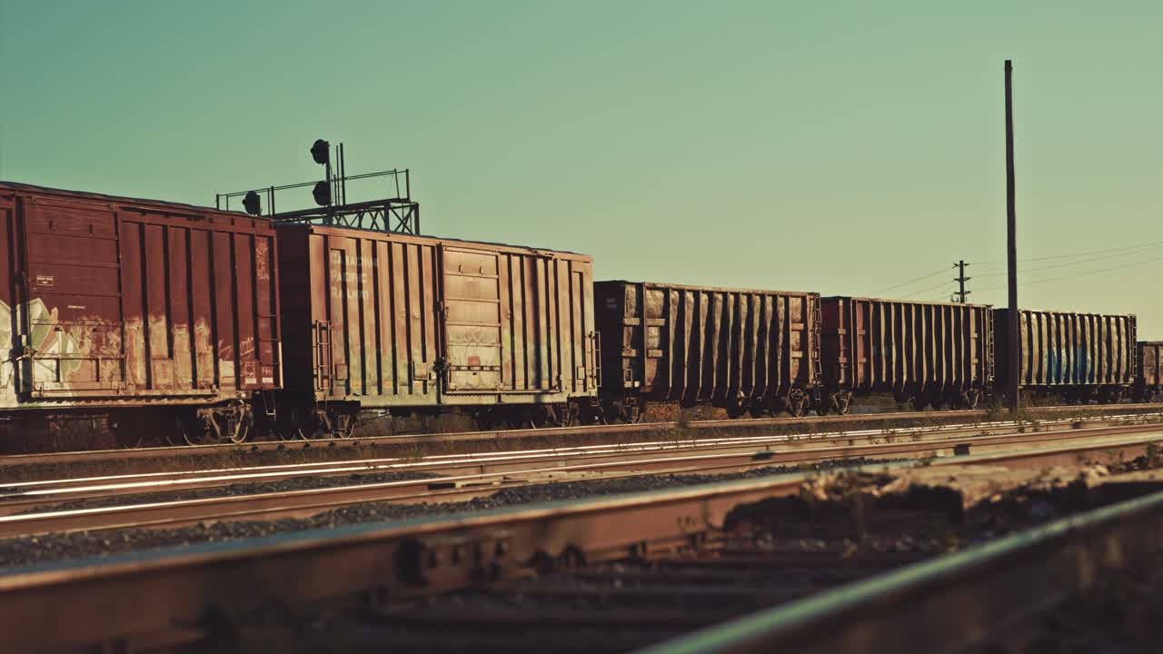Old Freight Train Tanker Cargo Cars Departing Empty Abandoned Industrial City Railway Yard. Locomotive Carts Leaving Refinery Station Rail Tracks during Golden Hour Sunset Dusk Cinematic ProRes 4k