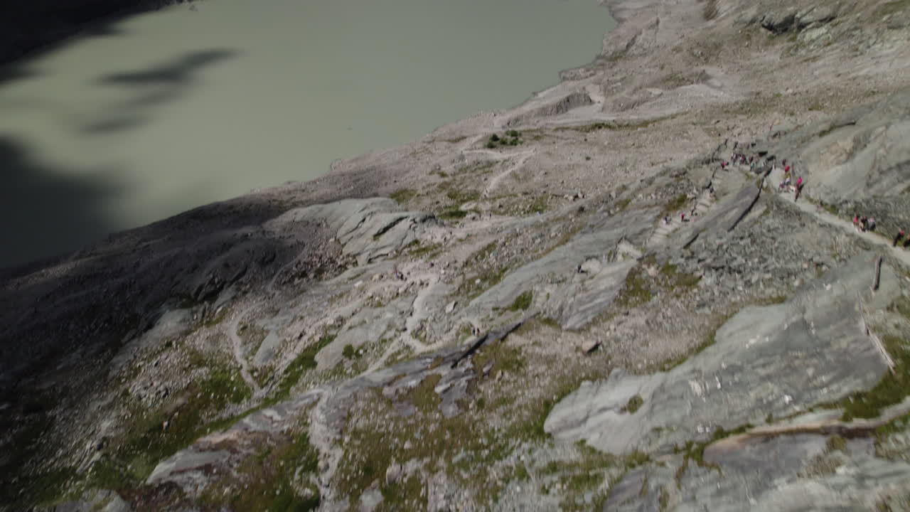 fotografía de un avión no tripulado que revela el agua del lago alpino del derretimiento del glaciar pasterze al pie de la montaña grossglockner en los alpes austriacos, camino de senderismo que conduce al glaciar pasterze
