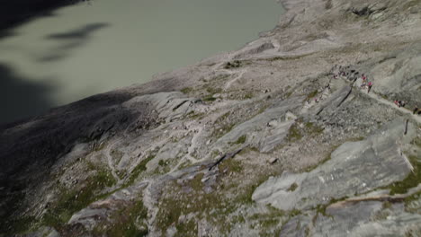 Drone-shot-revealing-alpine-lake-water-from-melting-glacier-Pasterze-at-the-foot-of-the-Grossglockner-Mountain-in-the-Austrian-Alps,-Hiking-trail-leading-to-Pasterze-Glacier