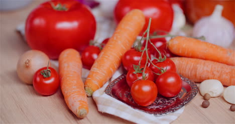 close up of various vegetables on table rotating fresh cherry tomatos carrot red onion and garlic 3