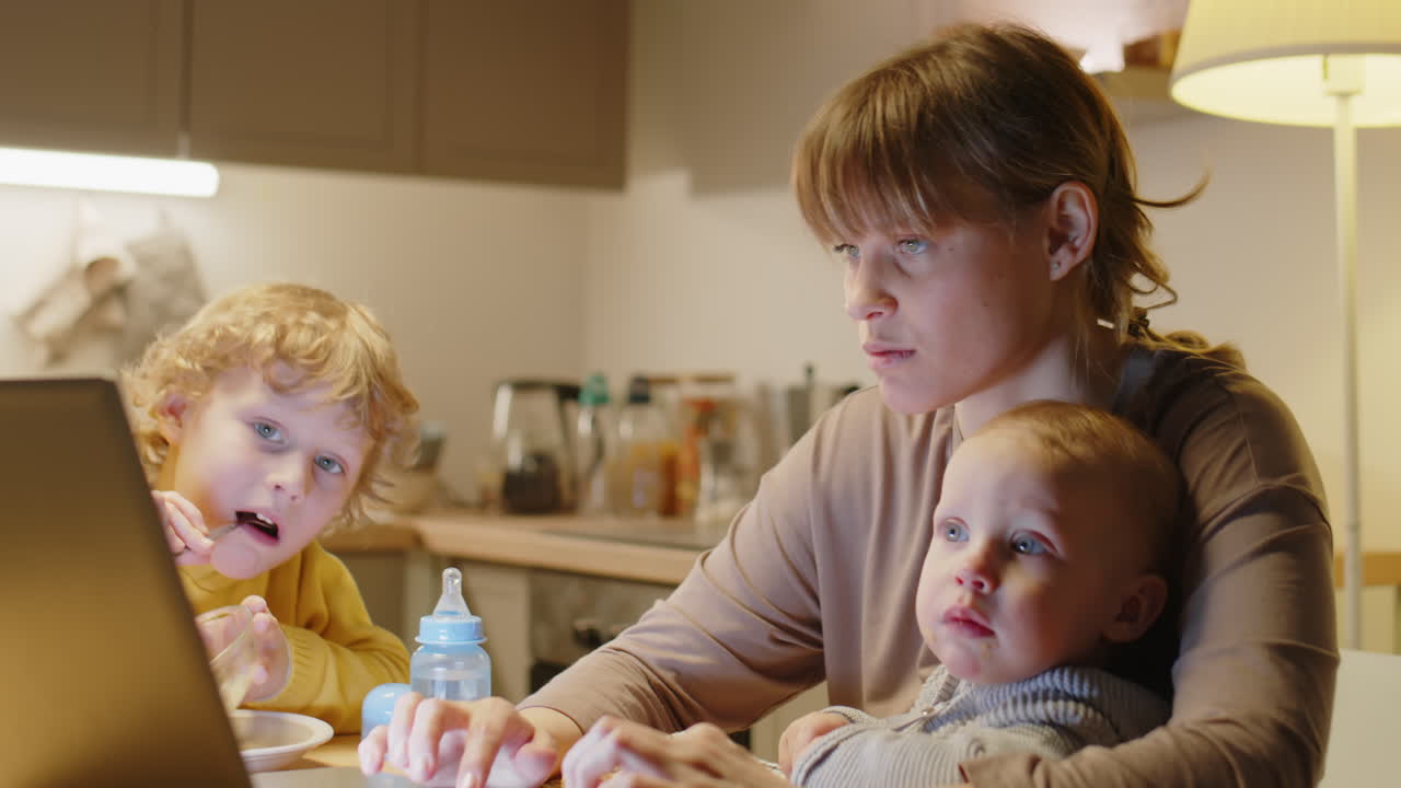 Mor til to barn jobber på laptop hjemme