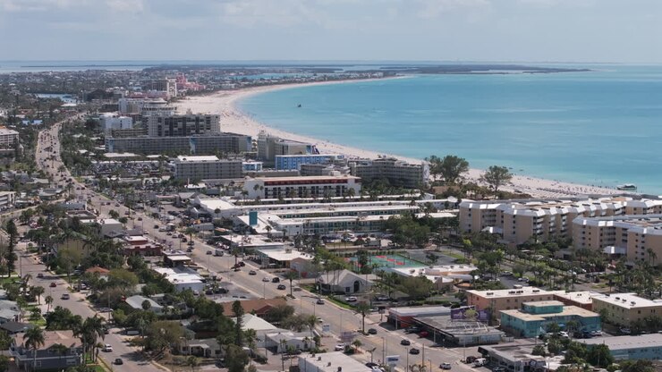 Aerial longshot vista of Gulf Boulevard on Saint Pete Beach facing south, showcasing beachfront hotels, resorts, white sand beach, and turquoise Gulf waters in Florida's premier beach destination