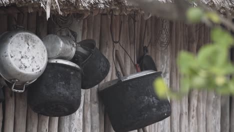 Leere-Alte-Kochtöpfe-Und-Kessel-Aus-Schwarzem-Eisen,-Die-An-Einer-Holzblockwand-In-Einem-Eingeborenenhaus-Im-Maya-Dorf-In-Mexiko-Hängen