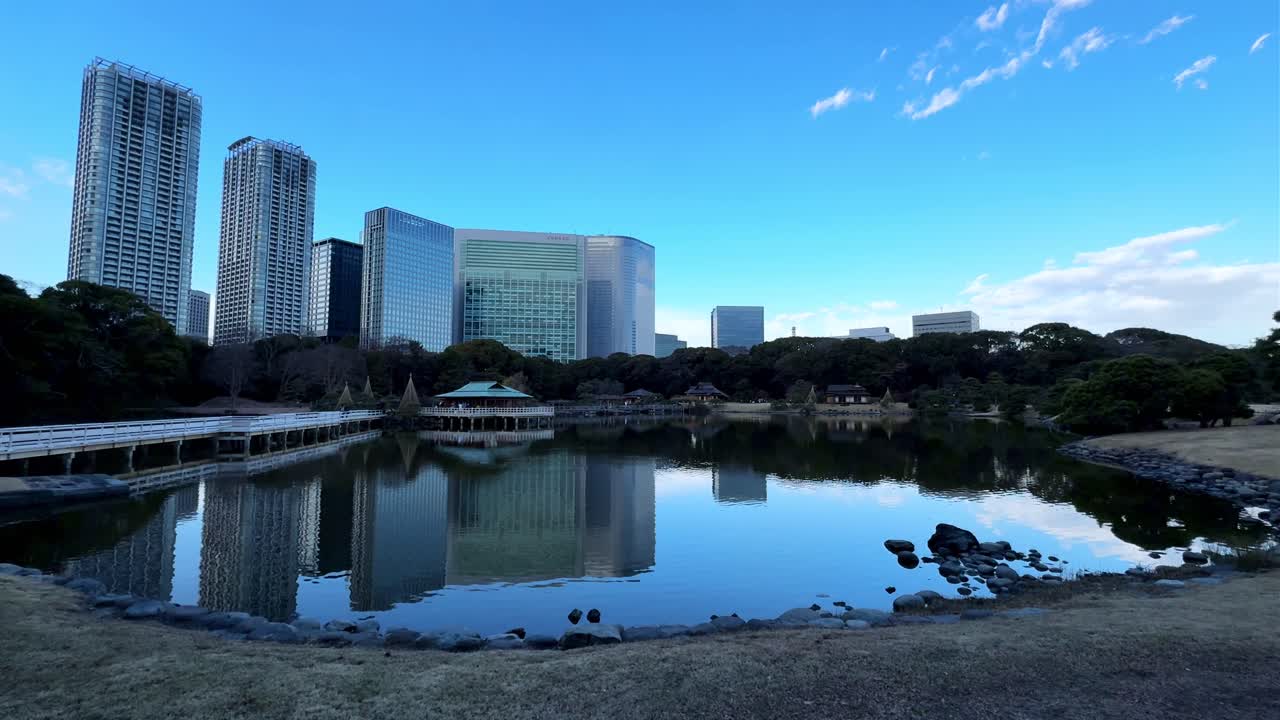 A peaceful garden landscape with tall buildings, a serene pond, and clear blue skies